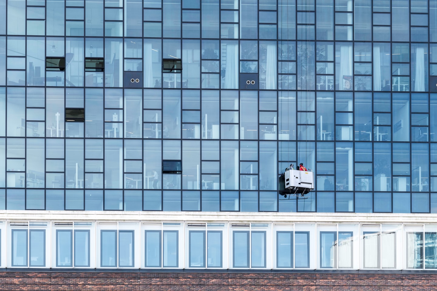 Fensterreiniger in einer Hängegondel wäscht ein modernes Gebäude.