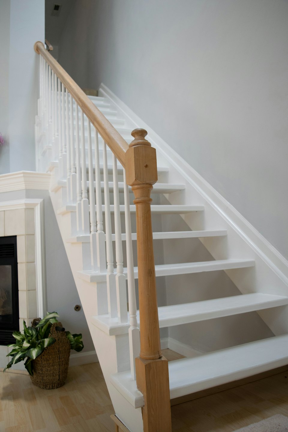 Moderne Innentreppe mit weißen Stufen und Holzhandlauf.