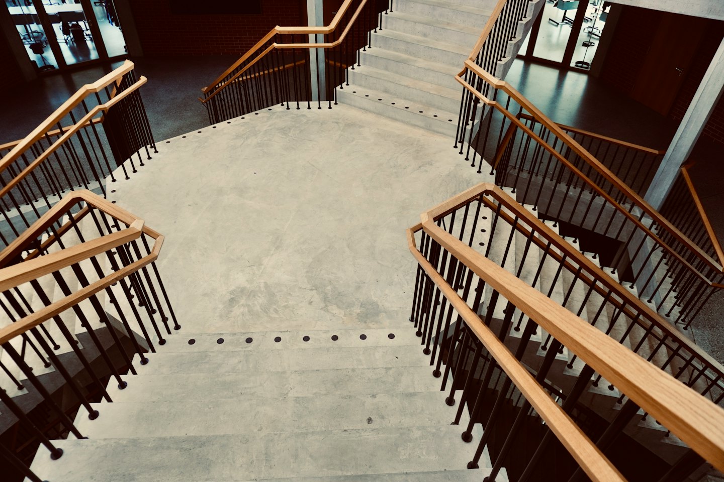 Moderne Betontreppe mit Holzhandlauf in einem Gebäude.