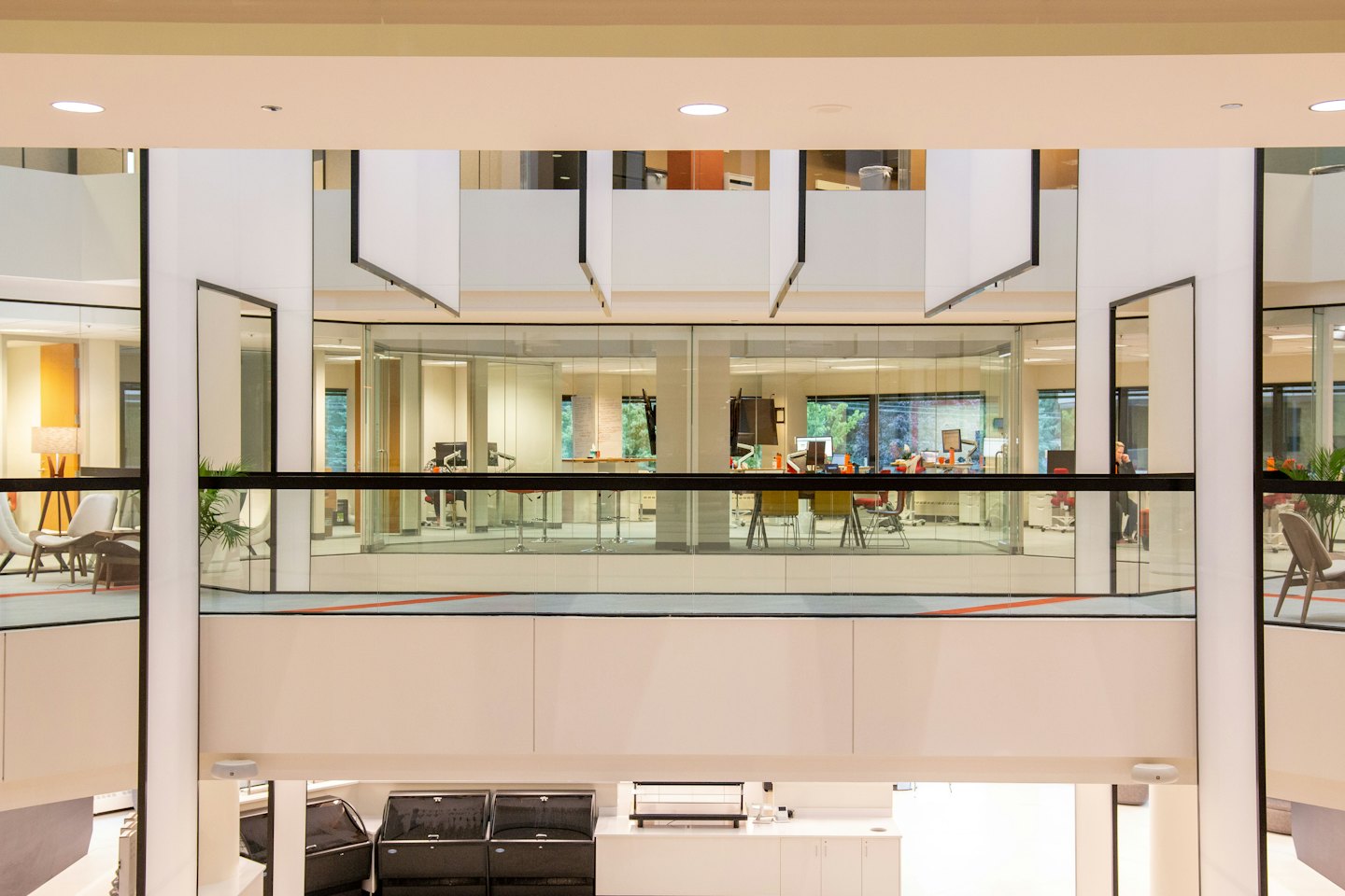Moderner Büro-Atrium mit glaswandigen Räumen und zeitgenössischen Möbeln.